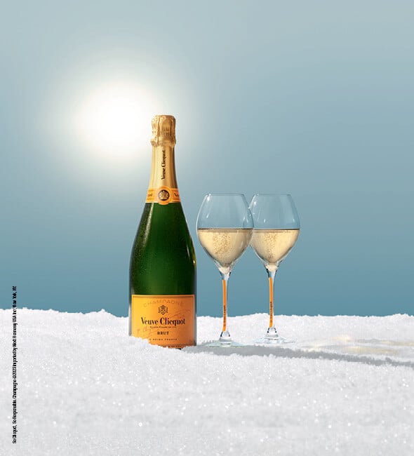 Veuve Yellow Label Champagne bottle with two glasses in the snow